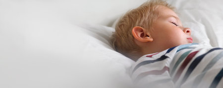 Young Child Sleeping on White Smooth Blanket. Little 3 Years Old Kids Sleep Alone in Cozy Bedroom. Soft Textile. Sleepy Blonde Hair Baby Boy Dreaming in a Bed at home. sign for banner. Space for textの写真素材
