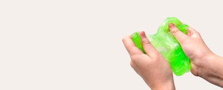 Hand Playing with textured slime on white background. Teen hand holding green shining slime with bubbles, stretching gooey substance. Teenage Girl squeezing slime toy to the sides. Liquid toy. handgumの写真素材