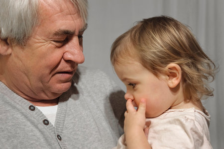 Gray Haired Old Man holds his little granddaughter in his hands. Family Relations of Elderly 60s Male and Baby Girl. Happy Senior Male and one year old GrandChild. Gentle Hug. Enjoy Moments of Life.の写真素材