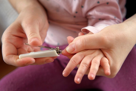 Mother use Nail Trimmer with baby hand. Mom cutting tiny fingernails. baby care concept. How to successfully clip your baby's nails. closeup. newborn hygiene. Clipping Child's Nails. front view.の写真素材