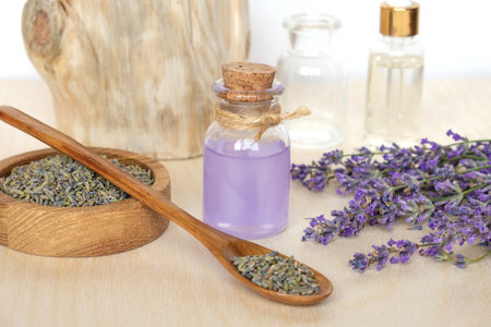 Dry lavender flowers in wooden bowl and bottle of essential lavender oil or infused water on white background. Natural organic ingredients for herbal cosmetics. Spa massage set, lavender product.の写真素材