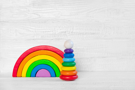Wooden toys banner with copy space for text. Colorful baby toys against a wooden white wall. Child mockup for design presentation. minimal composition. Kids room interior decoration. birthday party.の写真素材