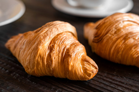 Coffee cup with croissant on a rustic dark wooden table. food series. Two tasty fresh croissants, jam, orange juice. Continental breakfast served with freshly baked pastry. close up view. good morningの写真素材