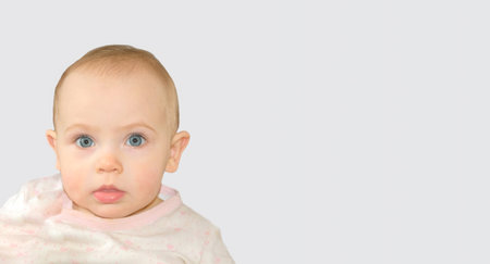 Close Up of Baby Child Face on Studio Background. Baby Girl Positive Emotion on Neutral Gray Color....