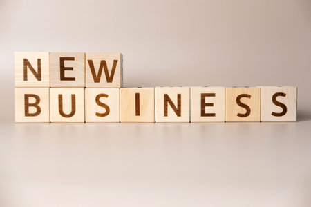The word NEW BUSINESS on wooden cubes on a beige neutral studio background. copyspace. Written. Text words matter. concept photo. career symbol. The concept of volume increase make business grow.の写真素材