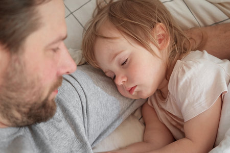 Father and his little daughter toddler girl sleeping together. Healthy sleep. Happy Loving family parent and child sleeping white bed at home. Authentic lifestyle fatherhood moments. single dad life.の写真素材