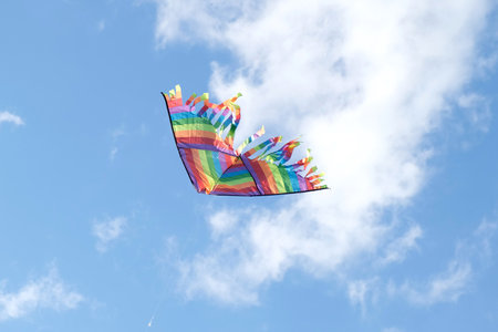Kite in a blue sky. Rainbow Delta Kite flying among the clouds. Happy growing years moment. outdoor time spending. Aspirations, target, inspiration concept. Freedom and summer holiday. childhood dreamの写真素材