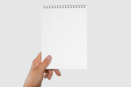 Female Hand Holding Notepad with Blank Page Isolated on Gray Neutral Studio Background. Close Up....