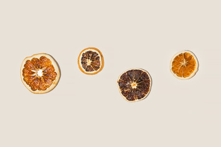 A set of dried orange slices isolated on a beige color. Top view, flat lay, copy space. Trendy neutral backdrop. Modern creative food background. Minimal Sliced candied citrus fruit. Holiday spicesの写真素材