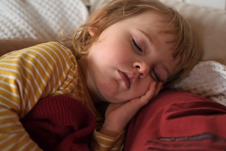 Peaceful adorable baby sleeping on a bed at home. Slumbering little child. Two year old girl sleeps peaceful at domestic room interior background. Serene dream. Cute face close up. Deep kid slumberの写真素材