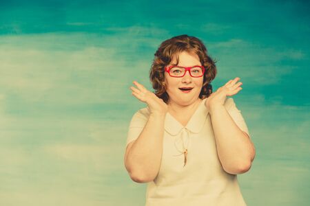 Attractive red-haired plump woman in a white suit adjusts red glasses on a yellow green background,...