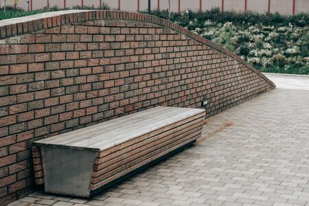 Lonely empty wooden bench on a brick wallの写真素材
