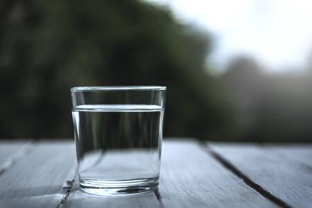 A glass with clean drinking water, a natural green background.