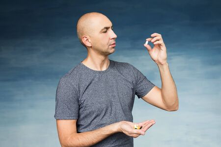 A bald man eats pills on the blue