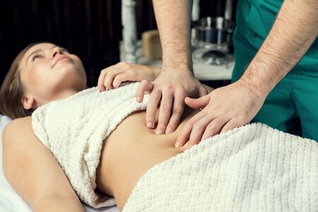 Hands of a man doing a massage of the abdomen.の写真素材