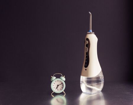 Oral irrigator and an alarm clock. on a black backgroundの写真素材