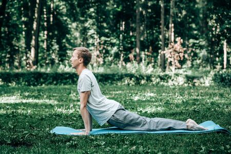 Young attractive man doing yoga in the park