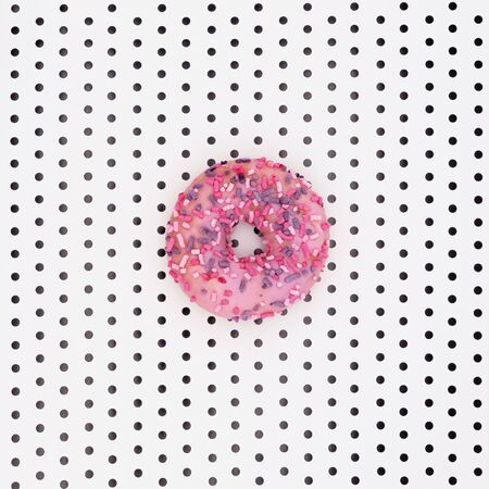 Delicious donut with icing and candy on a white background with black polka dots.の写真素材