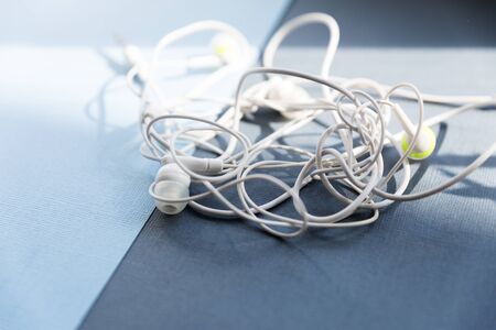 A few confusing drop-shaped headphones white on a blue background.の写真素材