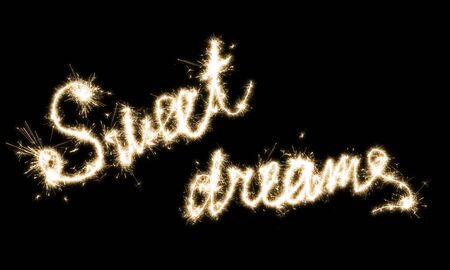 The inscription Sweet dreames on a black background with sparklersの写真素材