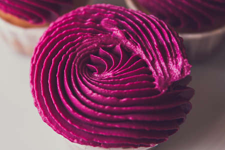 One cupcake with pink cream on a plate top view.