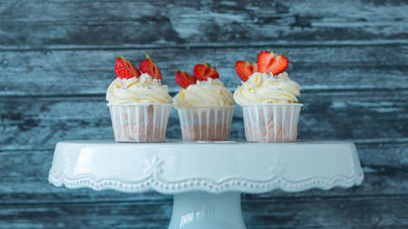 Delicious cupcakes with white cream decorated with strawberries on a gray background.の写真素材