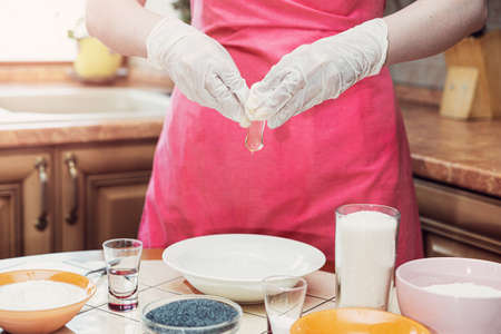 Female hands break an egg to make cake dough.