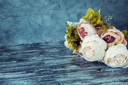 Blue-gray background with artificial flowers of pink peonies.の写真素材