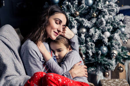 Young mother hugs daughter in pajamas holding her in her arms