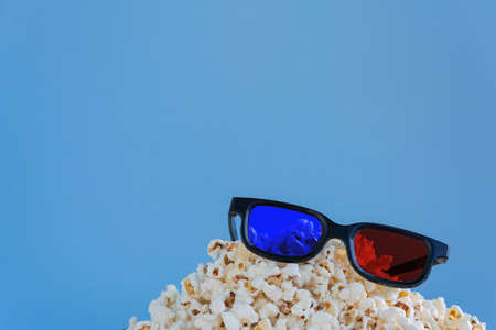 A slide of popcorn on a blue background and 3D glasses.