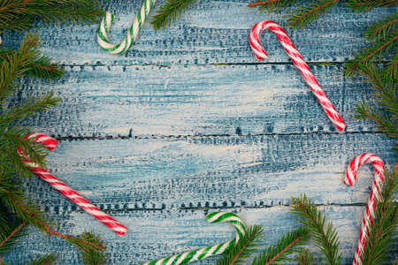 Christmas texture on a blue wooden background candy canes surrounded by spruce branchesの写真素材