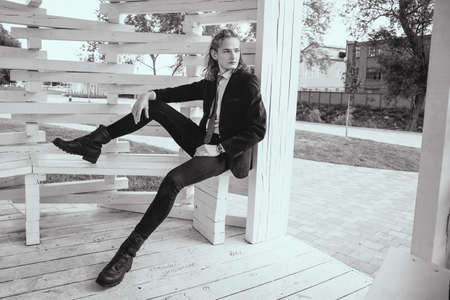Black-white portrait A portrait of young man in a black suit sits in a wooden arborの写真素材