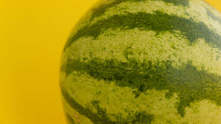 Not cut watermelon on a yellow background