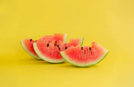Cut red watermelon with seeds on a yellow background