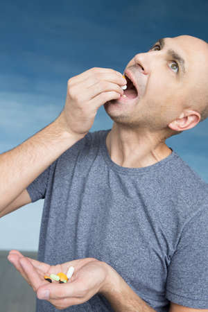 A bald man eats pills with greed.の写真素材
