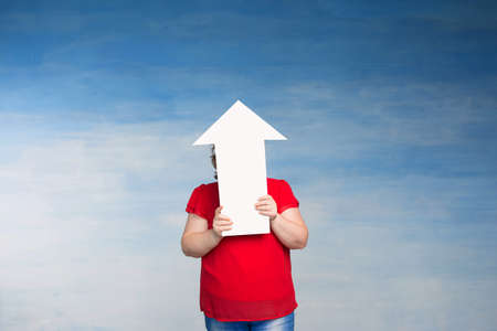 Pretty red-haired plump woman in a red T-shirt and covered her face with an arrow on a blue...