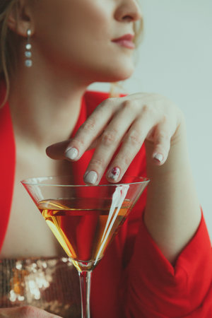 Beautiful blonde girl with a martini glass on a light background.の写真素材