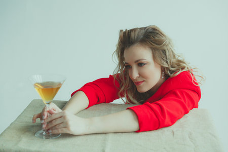 Beautiful blonde girl with a martini glass on a light backgroundの写真素材