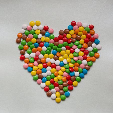 Heart of multicolored round candies on a gray backgroundの写真素材