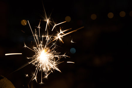 Bengal fire sparkles against the background of city lights, blurred bokeh. A lot of sparks.の写真素材
