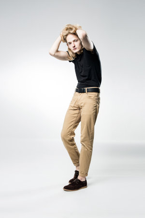A young handsome guy with long blonde hair, isolated on a light background.の写真素材