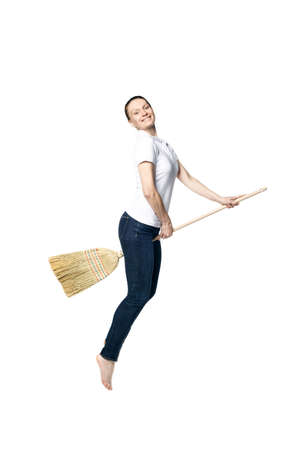 Beautiful woman in a white T-shirt flies on a broomstick like a witch and smiles, isolated on a white background.の写真素材