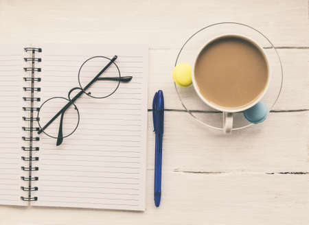 Light texture in white and blue colors: glasses, a notebook, pen and a cup of aromatic coffee with...