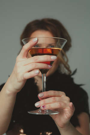 Girl holding a martini glass covering her face.の写真素材