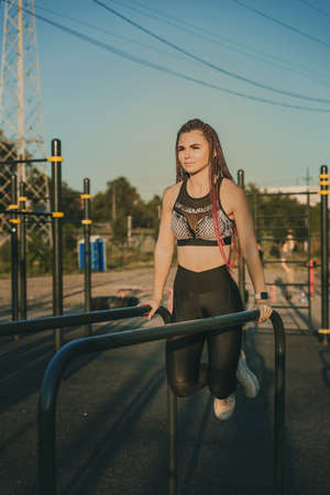 A young woman of athletic physique is doing an exercise on the uneven bars.の写真素材