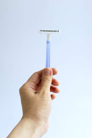 A female hand holds a disposable razor on a white background
