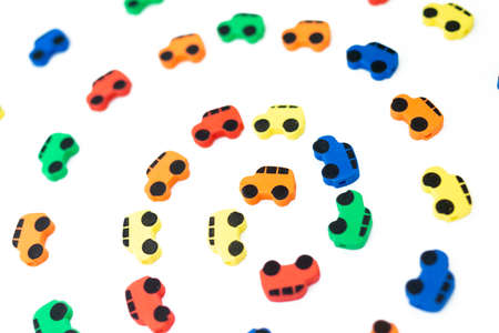 Texture of small multi-colored toy cars moving in a circle isolated on a white background, Top view...