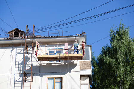 City Tula. Russia - July 07, 2021: A male house painter paints a residential building on a front...
