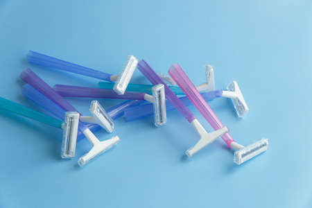 Set of multi-colored disposable razors on a blue background.