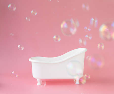 Empty white bathtub toy on a pink background and soap bubbles foam.